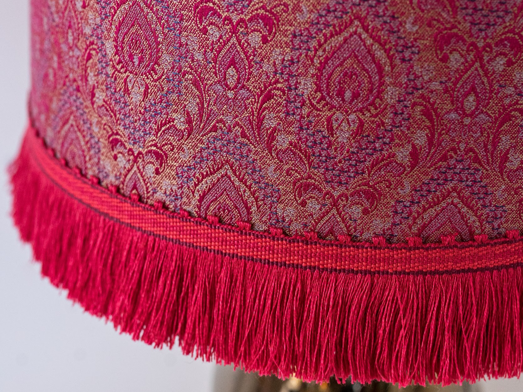Detail eines roten Brokatschirms mit Fransenborte