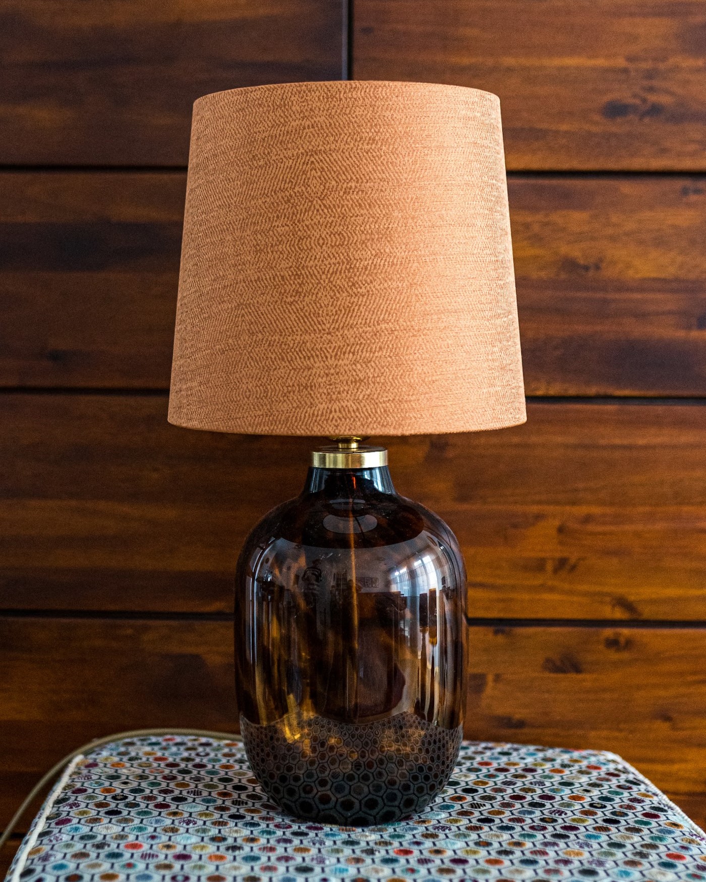 Lampe mit beigem Leinenschirm auf braunem Glasfuß